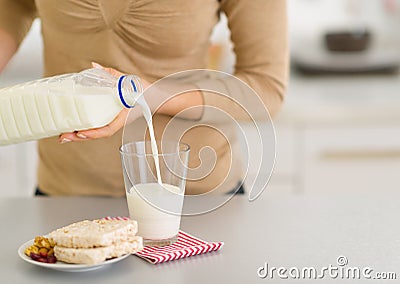 Closeup on young woman pouring milk into glass