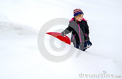 Cold child walking in the snow with sled