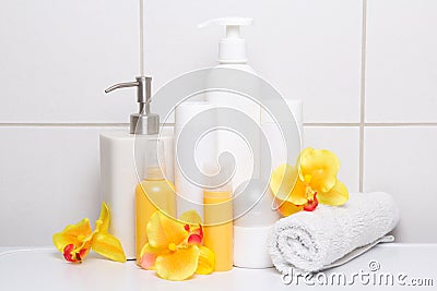 Collection of cosmetic bottles with orange flowers over white ti