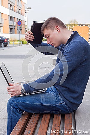 College student learning over the bench with laptop. Portrait of