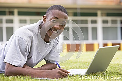 College student using laptop on campus lawn