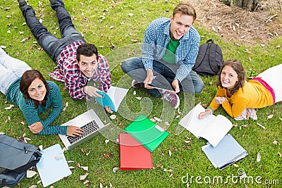 College students using laptop while doing homework in park