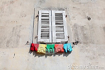 Colored shirts hanging to dry under the window pan