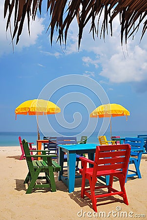 Colorful chair and table with yellow umbrella on the beach