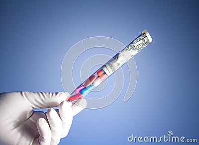 Colorful pills and dollars in test tube in a hand, cost of medical health care
