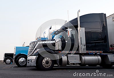 Commercial modern and classic semi trucks in truck stop line