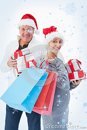 Composite image of festive mature couple in winter clothes holding gifts and bags