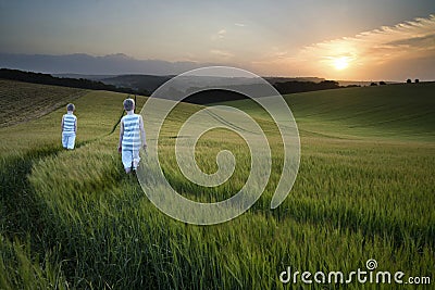 Concept landscape young boys walking through field at sunset in