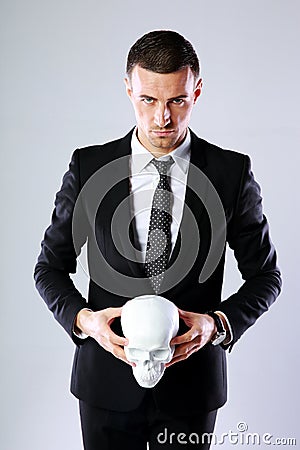 Confident businessman holding skull