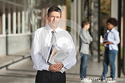 Confident Professor With Books Standing On College