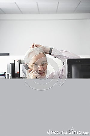 Confused Businessman On Call At Desk