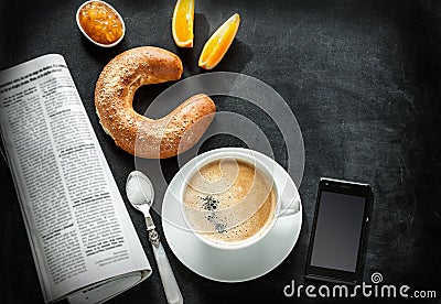 Continental breakfast and mobile phone on black chalkboard