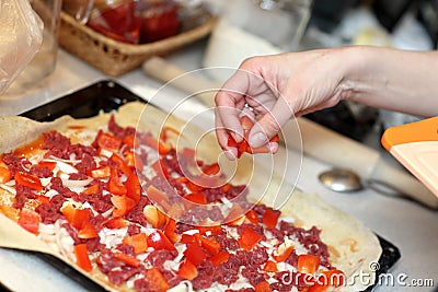 Cook putting pepper on pizza