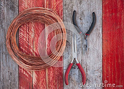 Copper wire and pliers on wood background