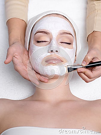 Cosmetician apllying mask on face of woman
