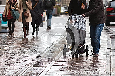 Couple with a baby buggy in the rainy city