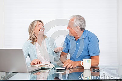 Couple At Dining Table Working on Laptop