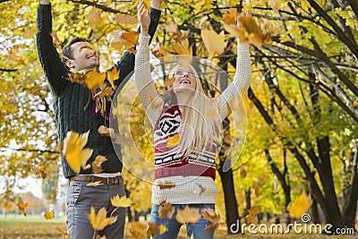 Couple enjoying falling autumn leaves in park