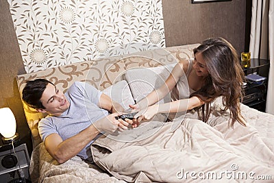 Couple fighting in bed over the tv remote control