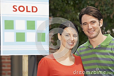 Couple In Front Of New Home With Sold Sign