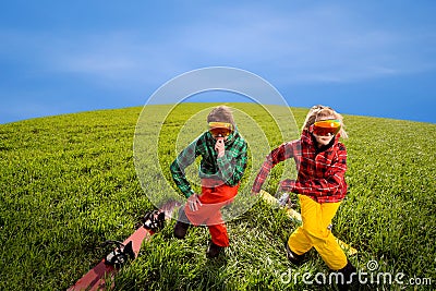 Couple having fun in ski suits with snowboards on the grass