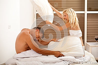 Couple having playful pillow fight in bed