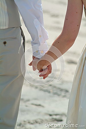 Couple holding hands during a beach wedding ceremony