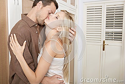 Couple hugging and kissing in bedroom.