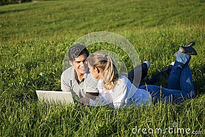 Couple with laptop on meadow
