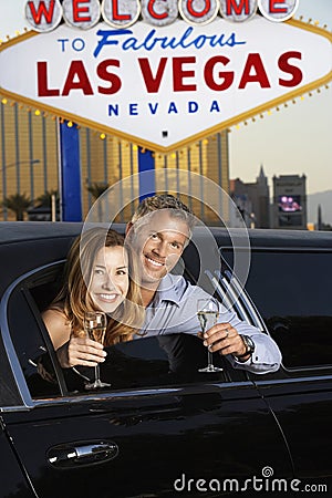Couple In Limousine With Champagne Flutes By Welcome To Las Vegas Sign