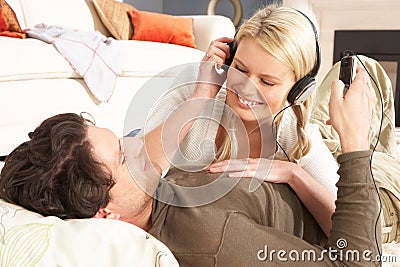 Couple Listening To MP3 Player Laying On Rug