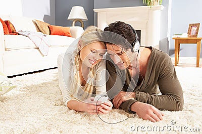 Couple Listening To MP3 Player Laying On Rug