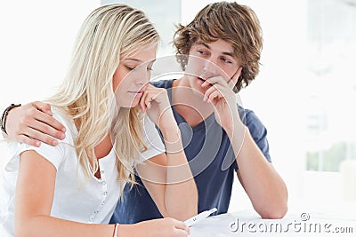 Couple looking worried as the girl holds a pregnancy test