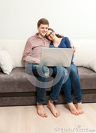Couple in love sitting on couch and watching movie on laptop