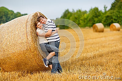 Couple in love on yellow hay field on summer evening.