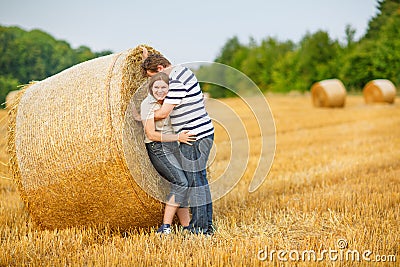 Couple in love on yellow hay field on summer evening.