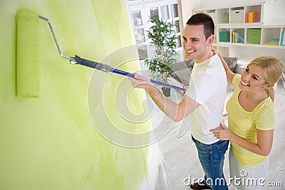 Couple painting wall with paint roller