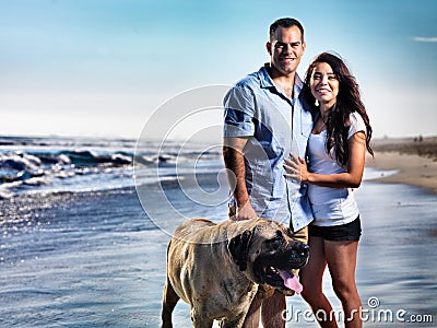 Couple with pet dog posing on the beach.