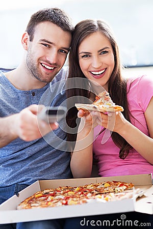 Couple with pizza and TV remote