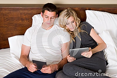 Couple reads tablet computers in bed