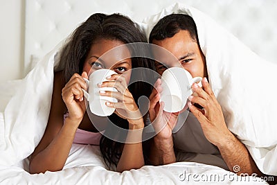 Couple Relaxing In Bed With Hot Drink