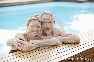 Couple Relaxing On The Edge Of Swimming Pool