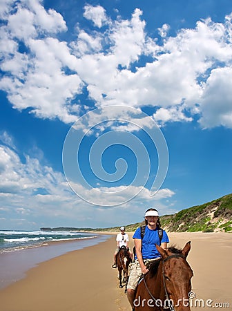 Couple of riders on beach under dramatic skies