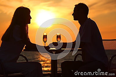 Couple s silhouettes on sunset sit at table