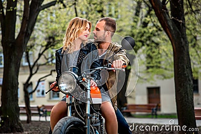 Couple sitting on the motorcycle in the city park