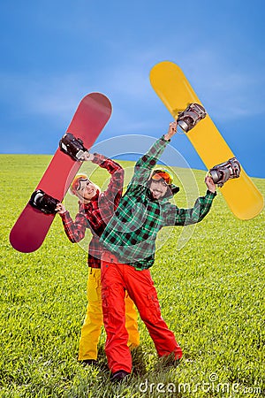 Couple in ski suit having fun with snowboards on the grass in gr