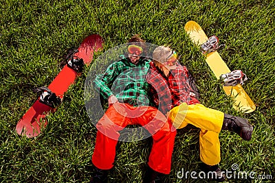 Couple in sportswear with snowboards lying on the grass