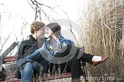 Couple Touching Noses On Park Bench