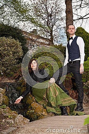 Couple in Victorian clothing near waterfall in park