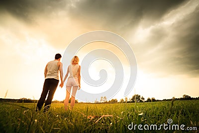 Couple walking through the field and holding hands